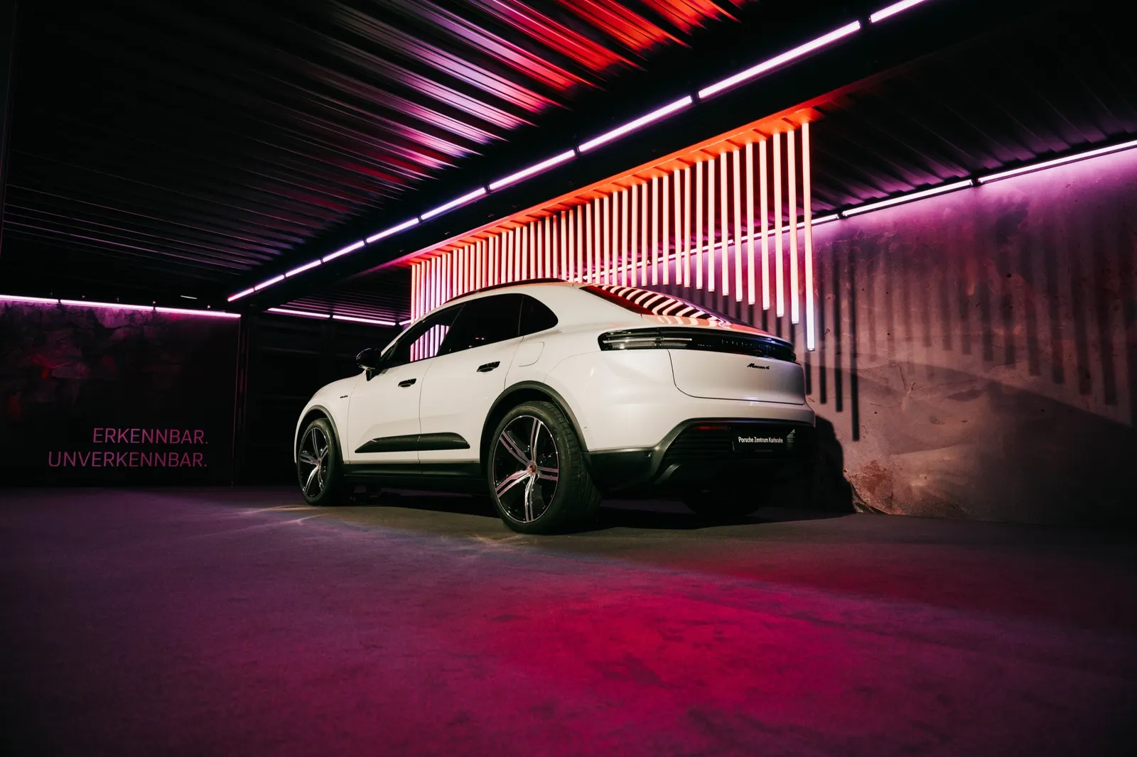 Weißer Porsche Macan im rot beleuchteten Hangar