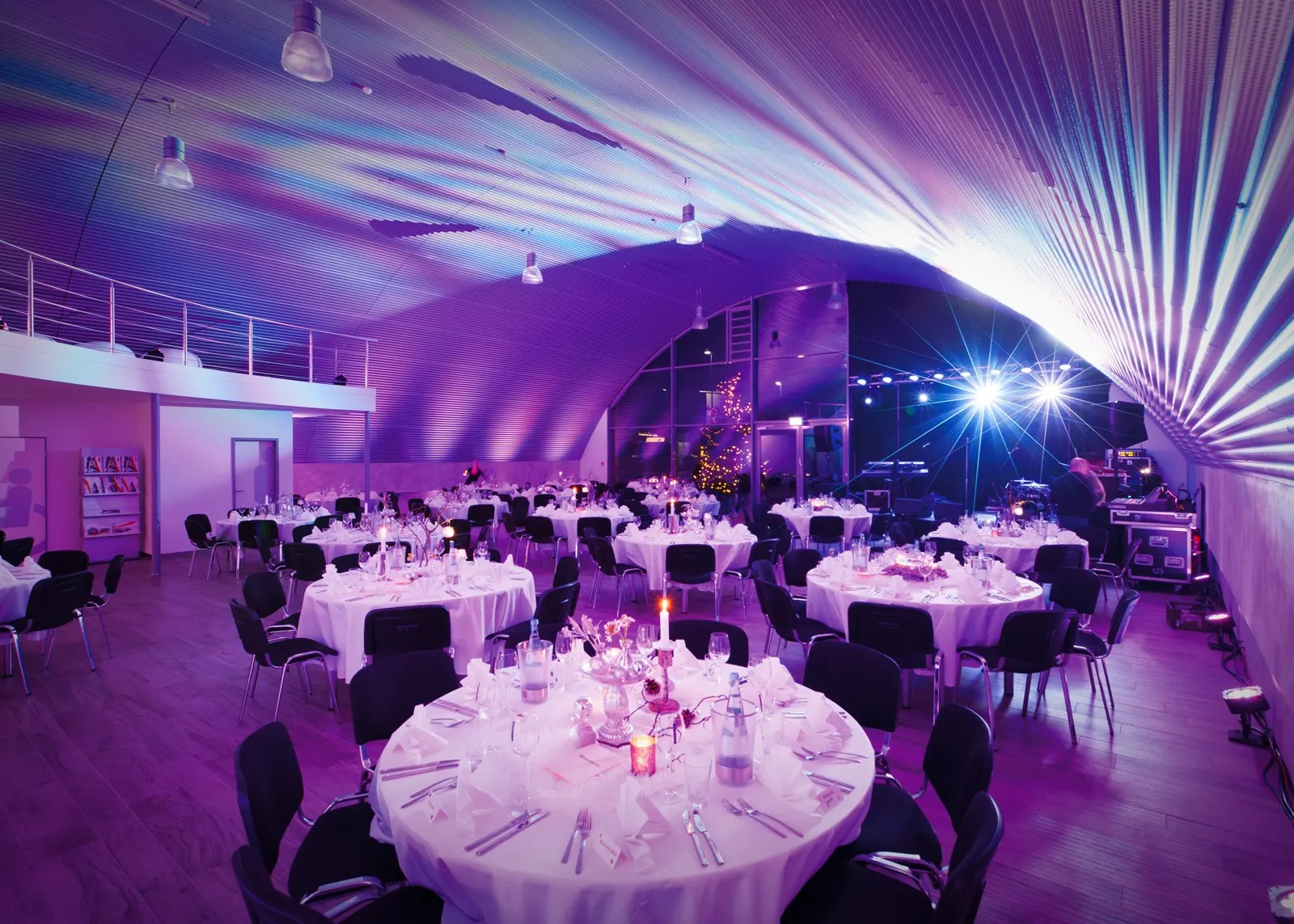 Gala-Tafeln unter violetten Lichtwellen am Bogendach