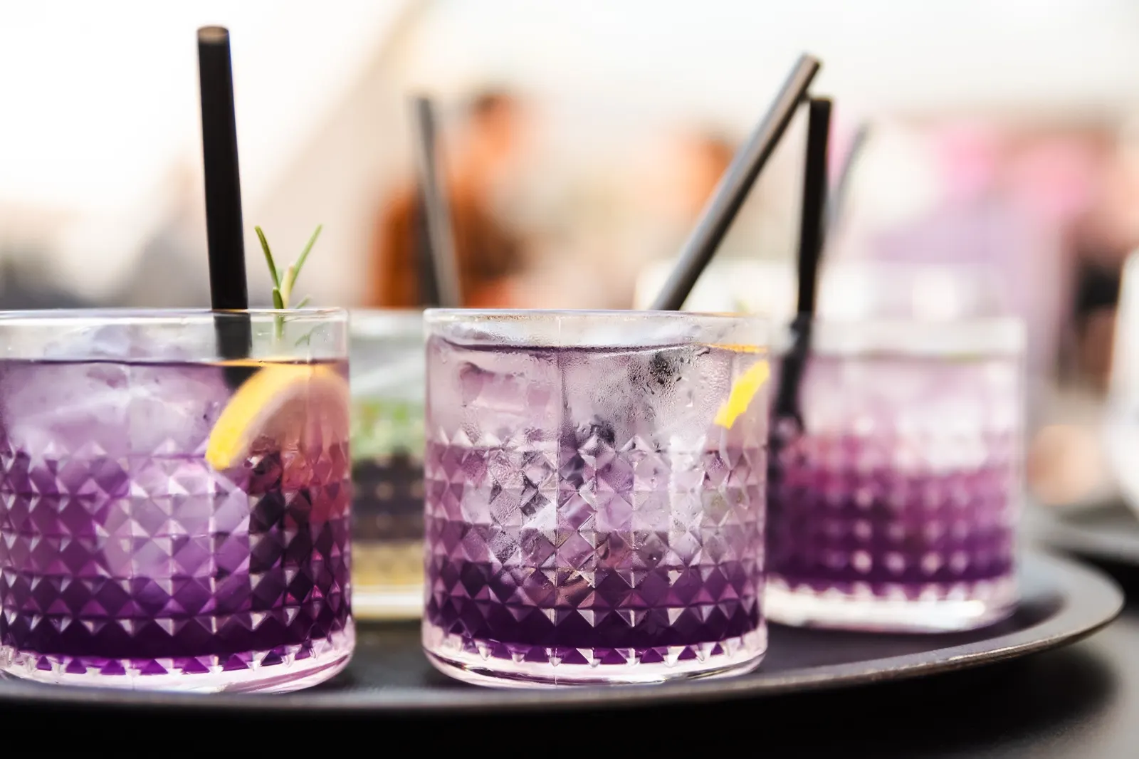Violette Cocktails mit Strohhalmen auf einem Tablett