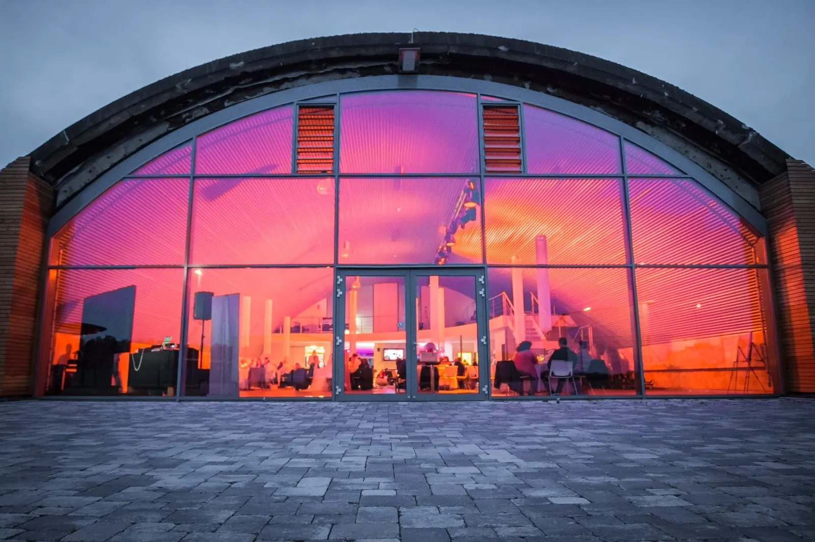Glasfront des Hangars in pinkem Licht in der Dämmerung
