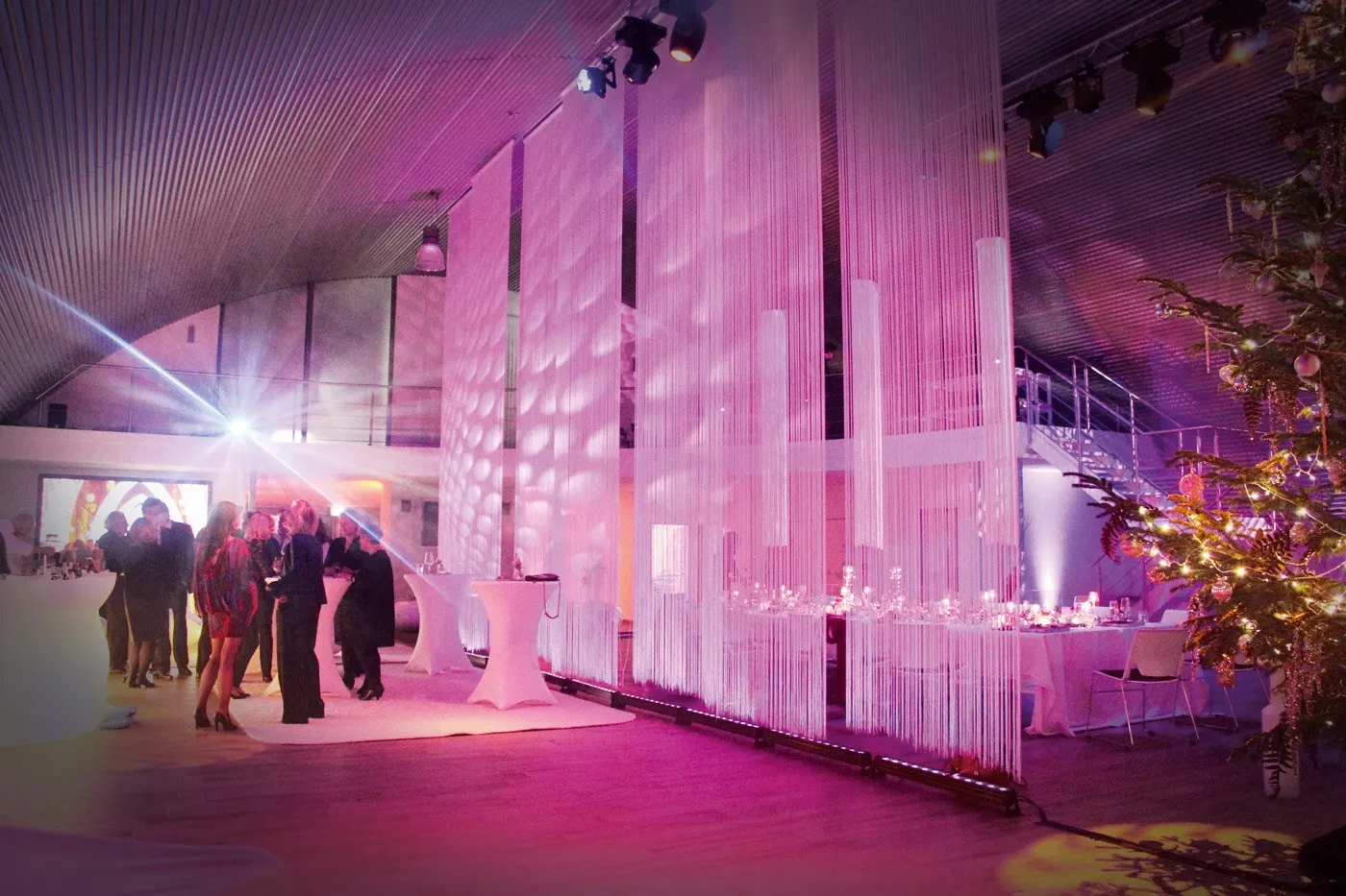 Feiernde Gäste vor einem pink beleuchteten Lichtfaden-Vorhang