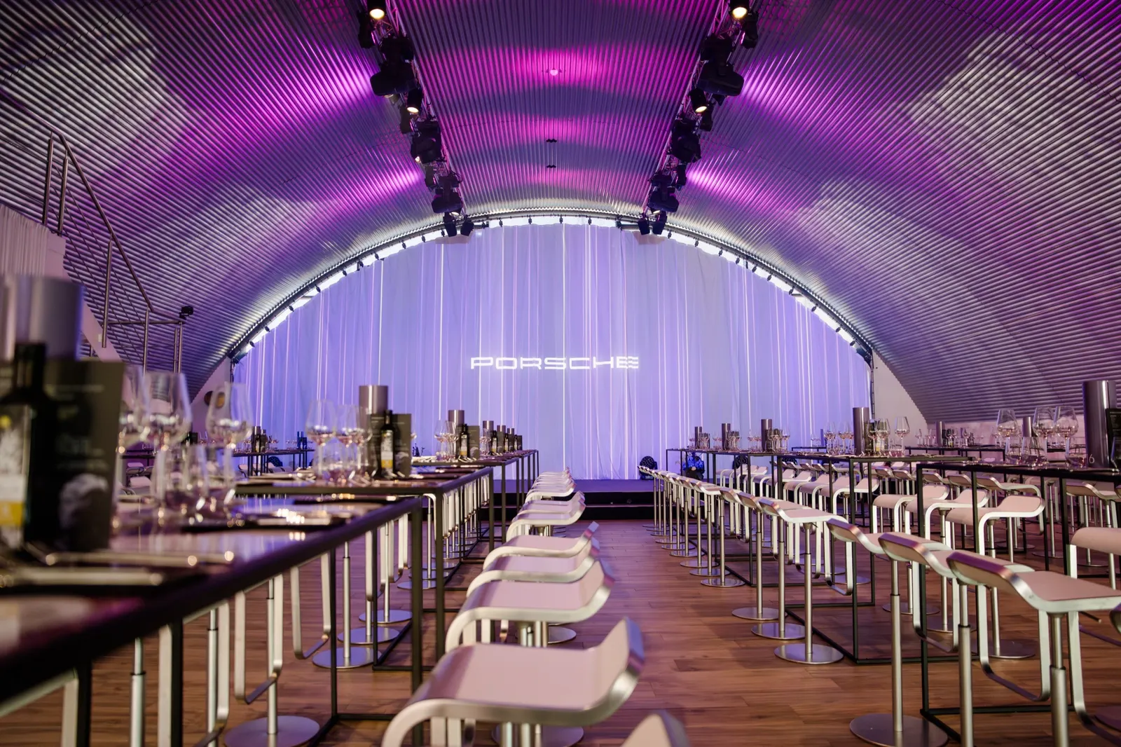 Bühne mit Porsche-Schriftzug und lange Tafeln im violetten Licht