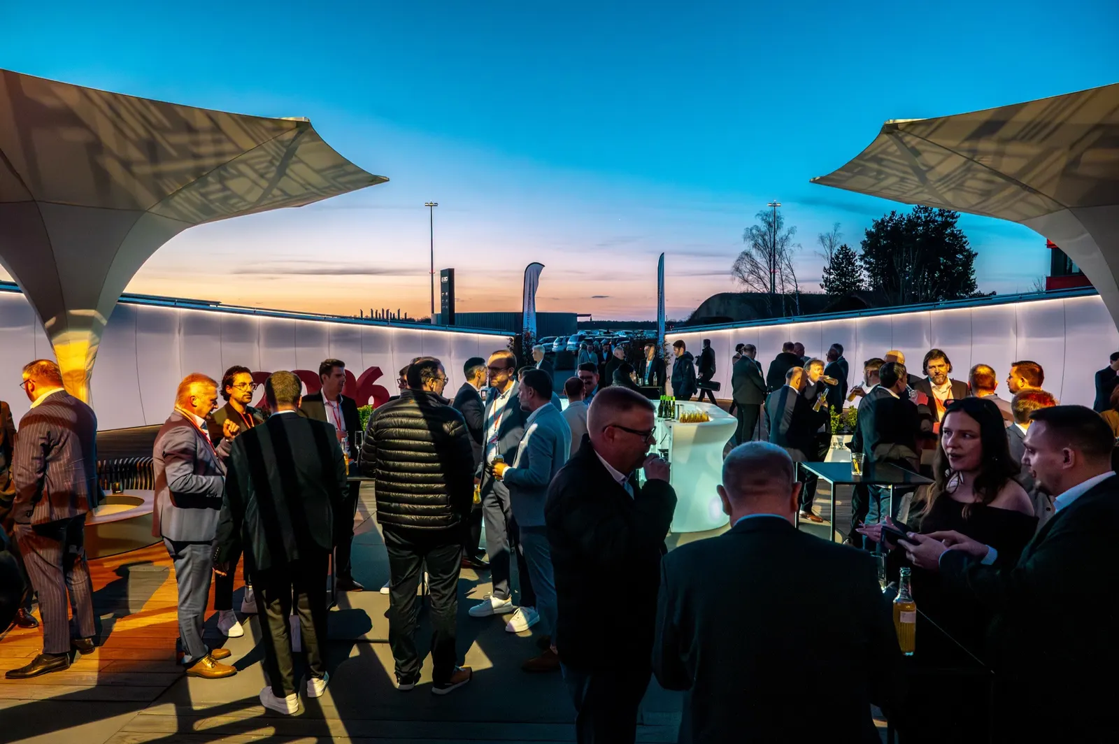 Abendempfang auf der Terrasse mit Gästen unter Sonnensegeln bei Sonnenuntergang